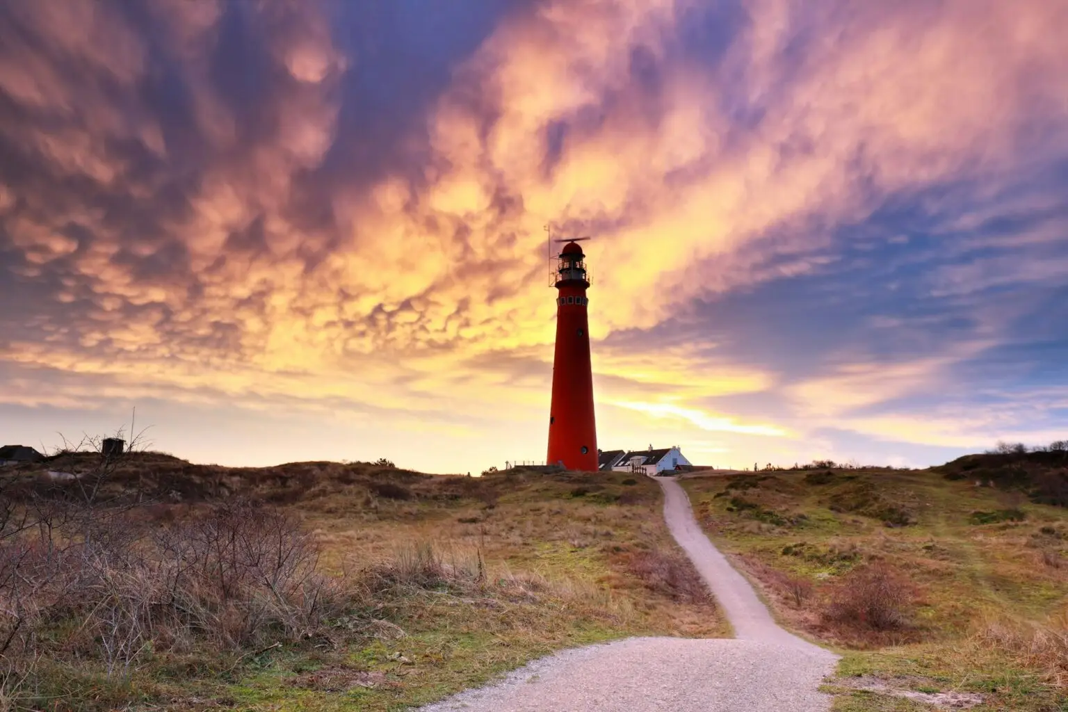 dramatic mammatus clouds over red lighthouse